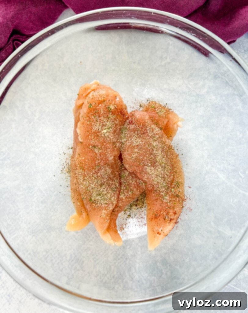 raw seasoned chicken tenderloins in a glass bowl