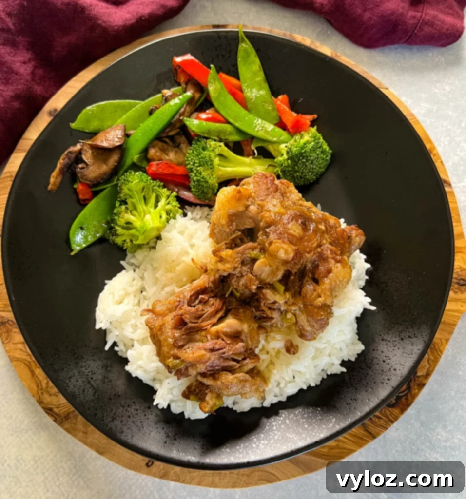 Plated oxtail dish featuring tender meat bathed in rich gravy, accompanied by fluffy white rice and fresh green vegetables