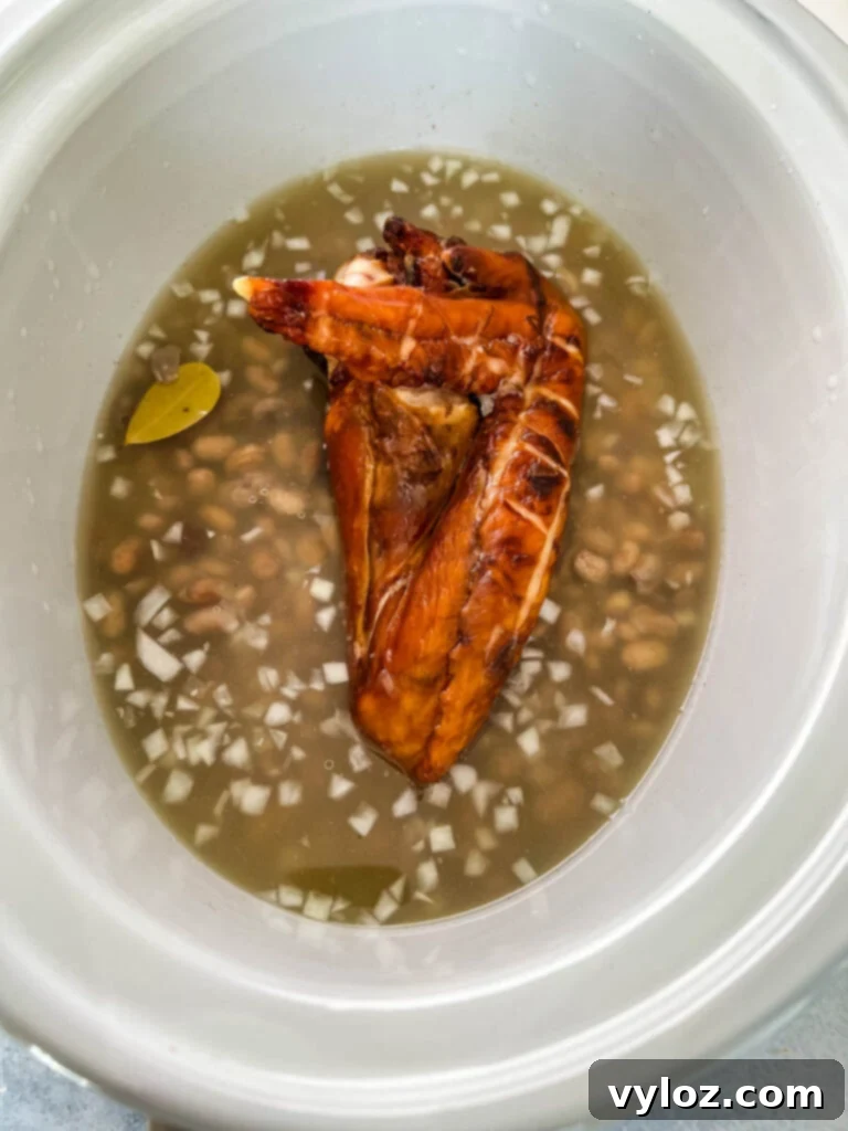 broth, smoked turkey, dry pinto beans, onions, bay leaves, and garlic in a slow cooker crockpot