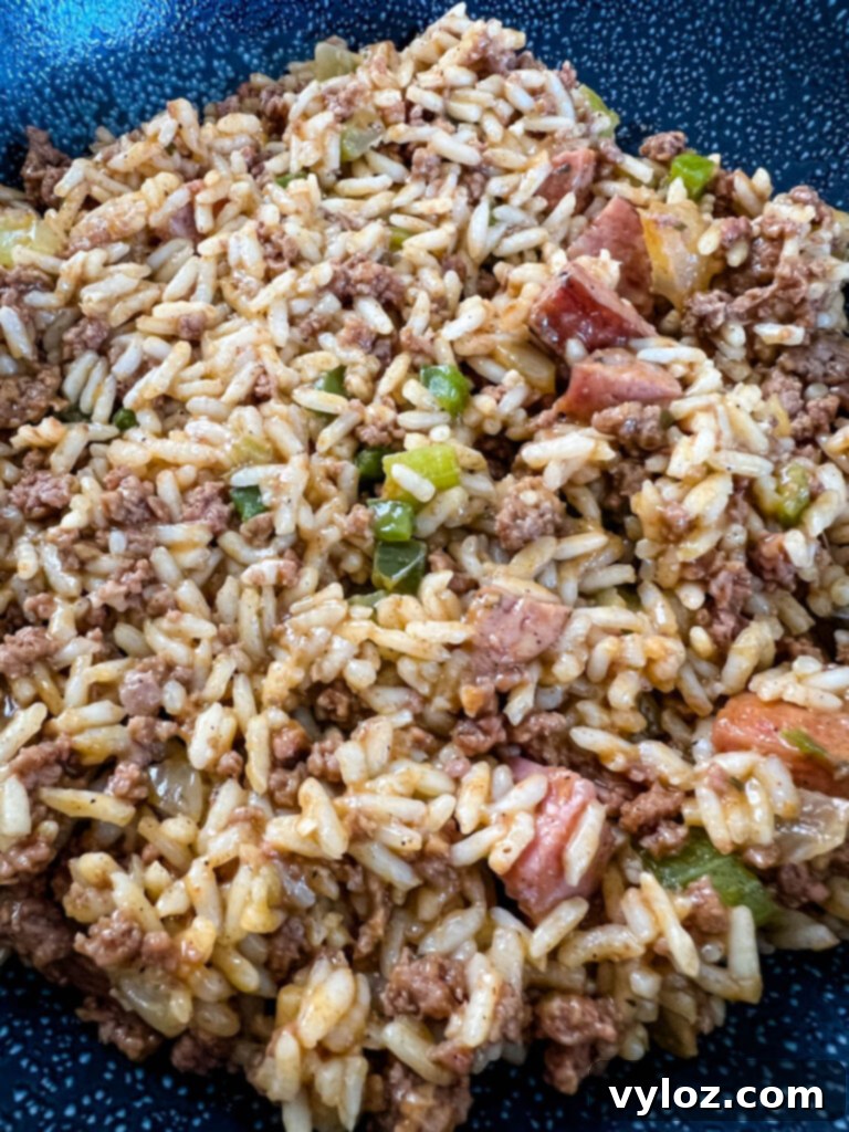Cajun Ground Beef and Rice 14 Cajun dirty rice in a cast iron skillet, garnished with fresh herbs, ready to be served.