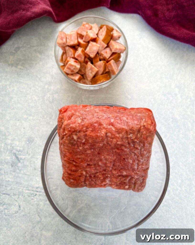 Cajun Ground Beef and Rice 3 Raw ground beef and sliced andouille sausage in separate glass bowls, ready for cooking.