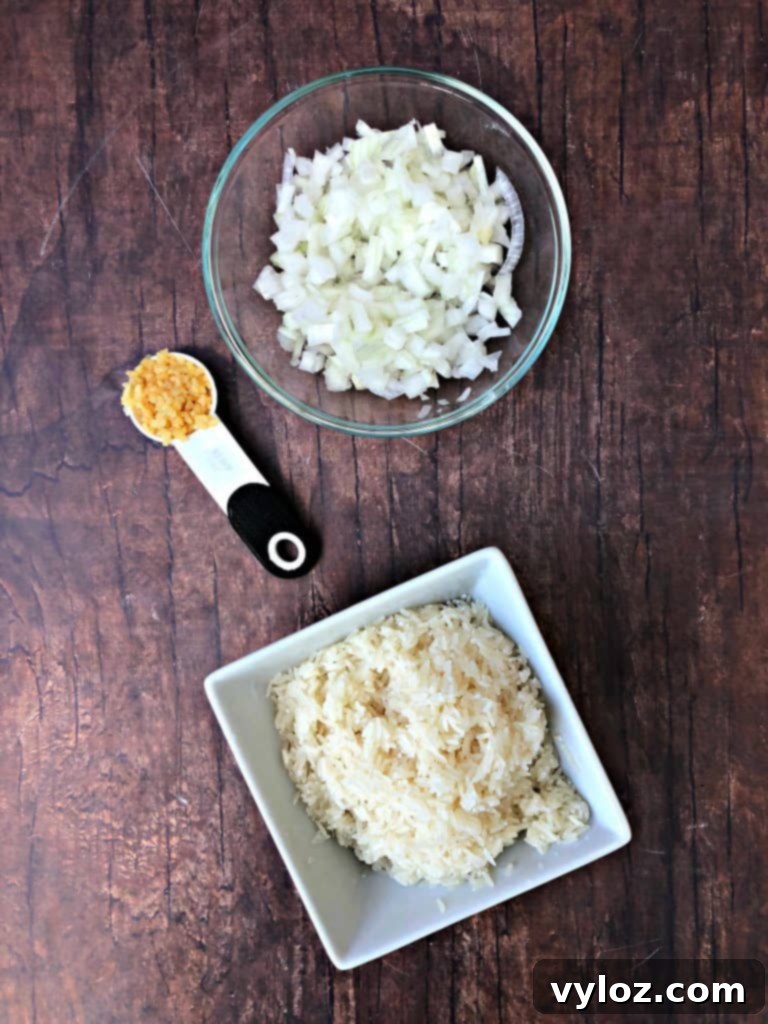 Instant Pot Arroz con Pollo Drumsticks 3 A close-up shot of fresh garlic cloves, sliced onions, and uncooked white rice, key aromatic and staple ingredients for Instant Pot Arroz con Pollo.