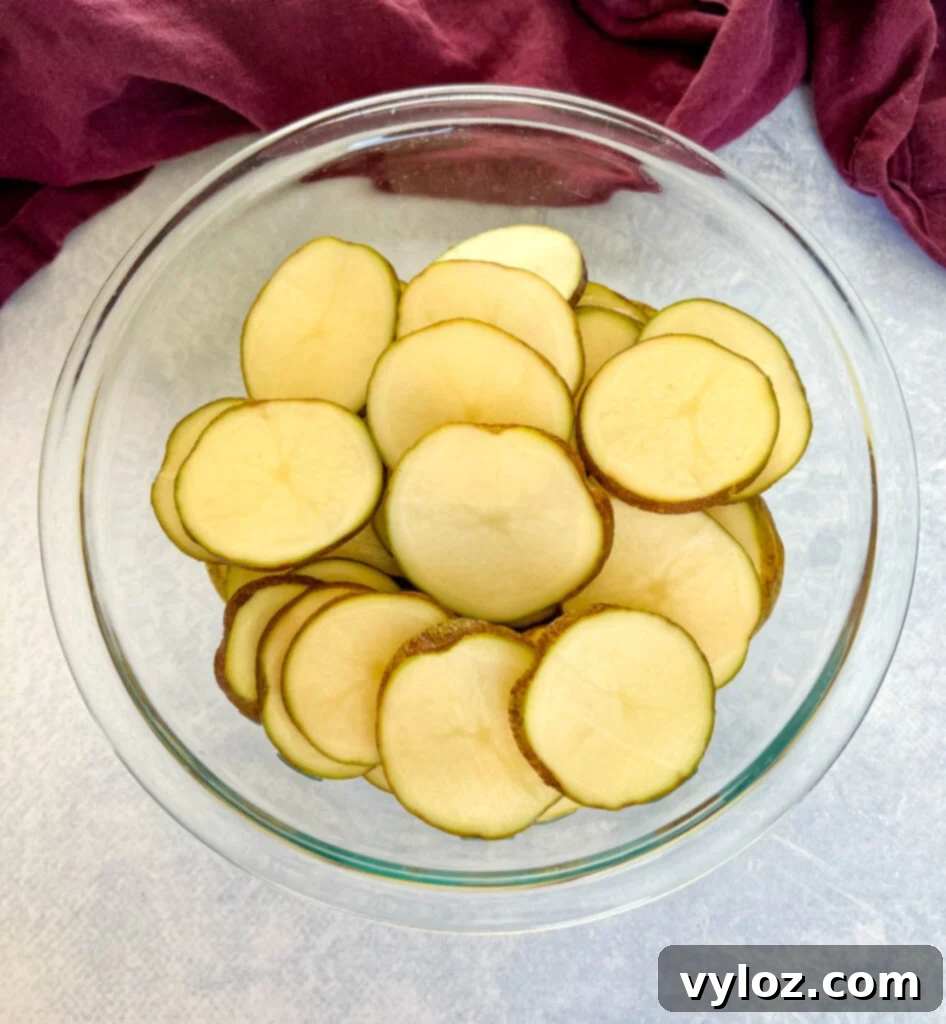russet potatoes sliced into rounds in a glass bowl