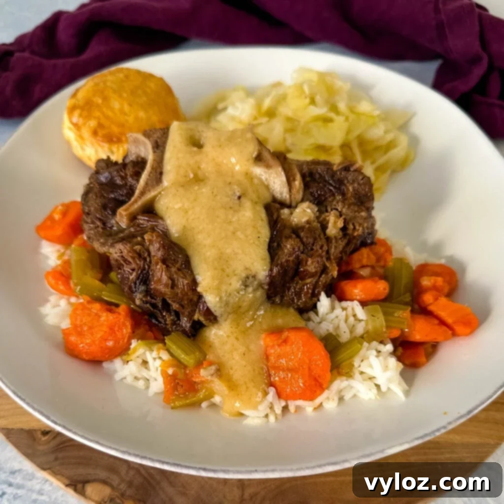 Plated beef neck bones with gravy, a side of cabbage, rice, and carrots
