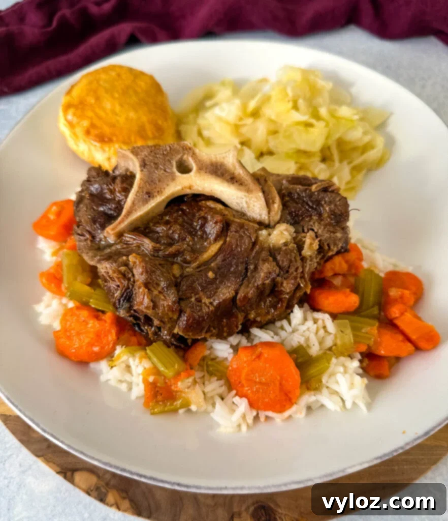 Plated beef neck bones with gravy, a side of cabbage, rice, and carrots