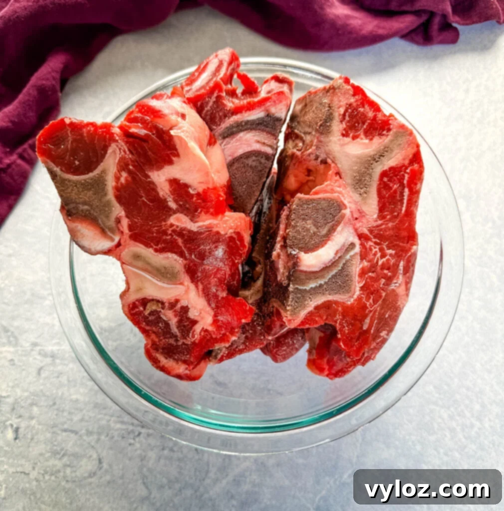Raw beef neck bones neatly arranged in a clear glass bowl