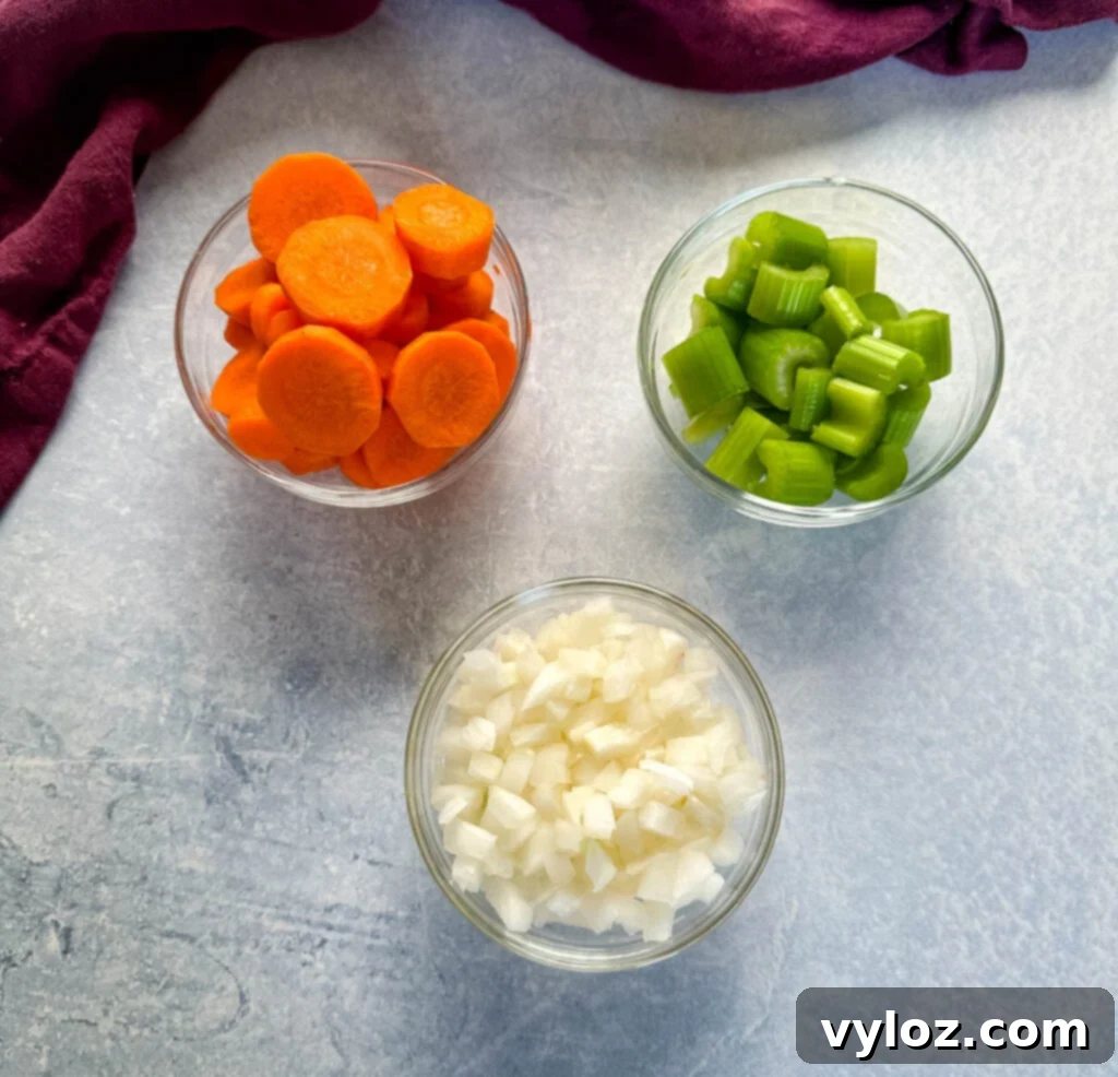 Freshly chopped carrots, celery, and onions presented in individual glass bowls