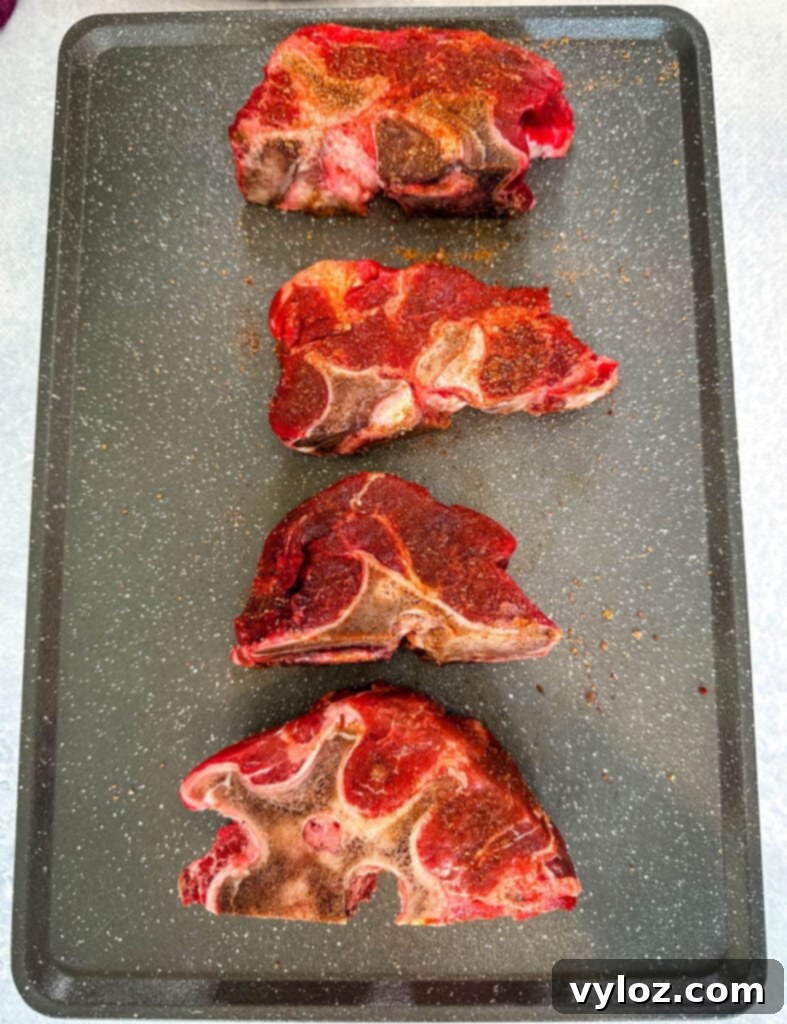 Raw seasoned beef neck bones arranged on a sheet pan, ready for searing