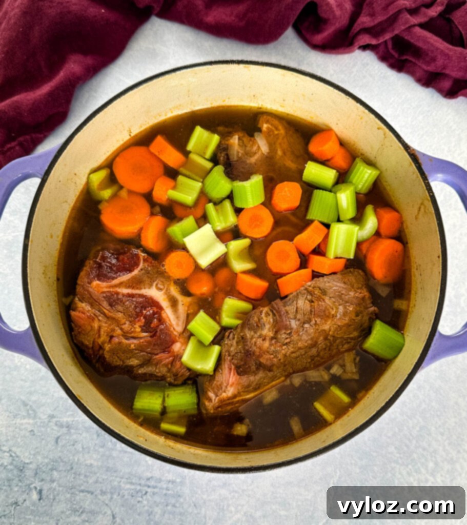 Beef neck bones simmering in a pot with chopped vegetables