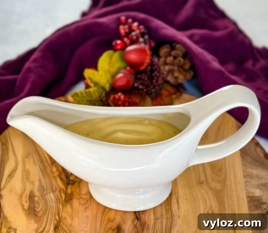 Dripping-Free Golden Gravy 6 A elegant white gravy boat filled with golden yellow gravy without drippings, placed on a dark background, ready for serving.