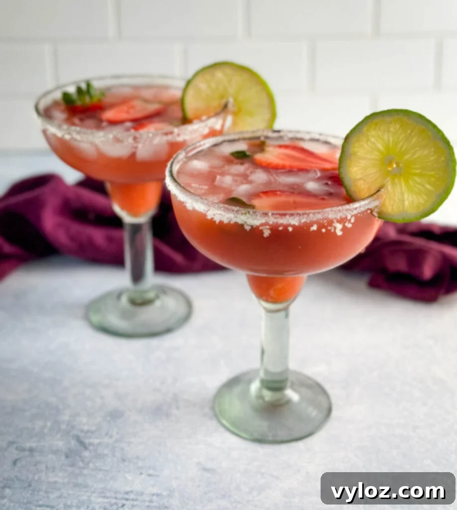 The Ultimate Hennessy Margarita 11 Hennessy margarita in a glass with strawberries and lime