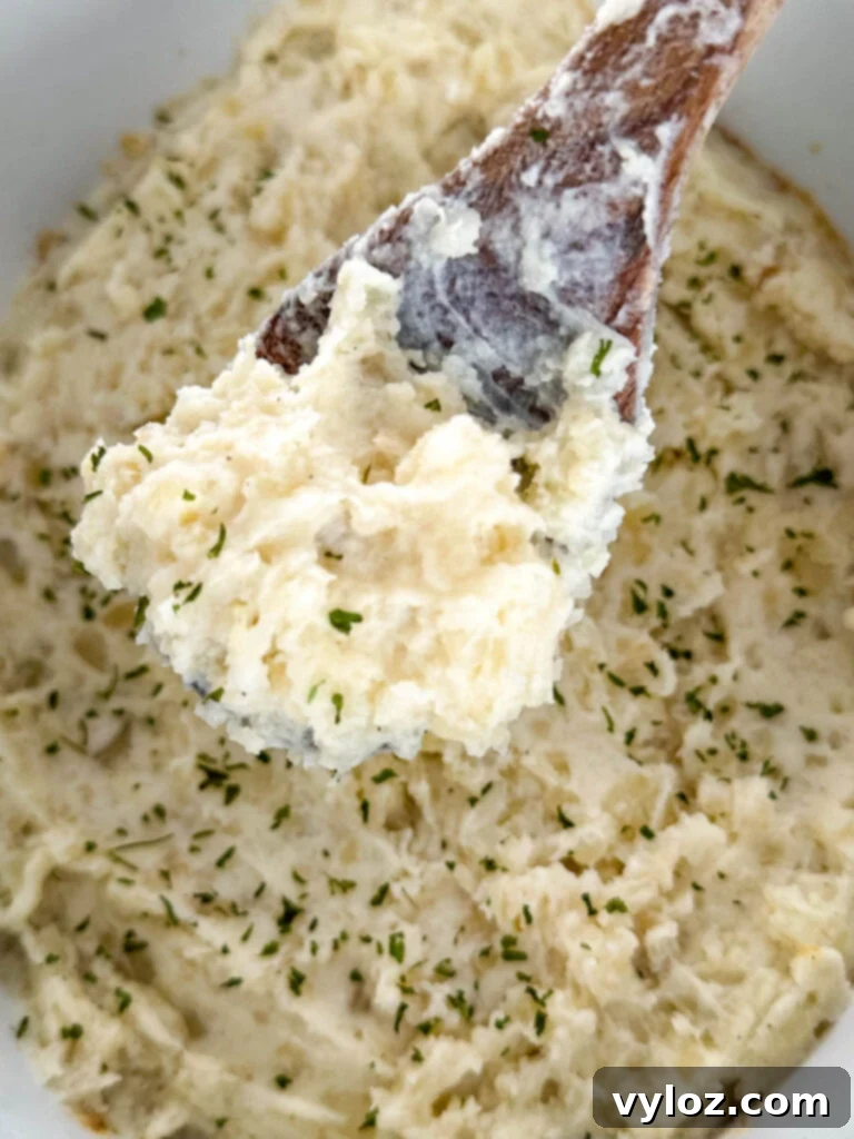 A wooden spoon serving a generous portion of creamy Crockpot slow cooker mashed potatoes, highlighting the smooth texture.