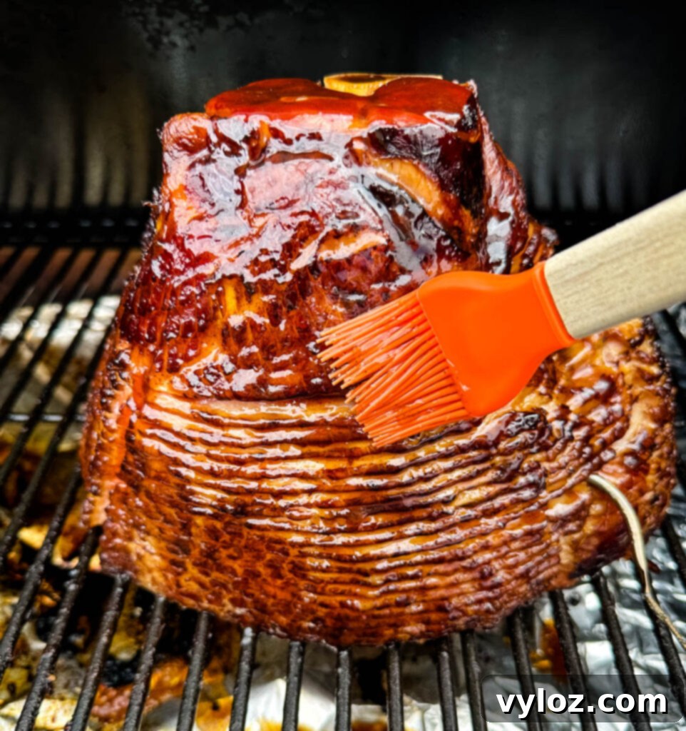 Traeger smoked ham on a pellet grill, generously brushed with honey brown sugar glaze and shimmering
