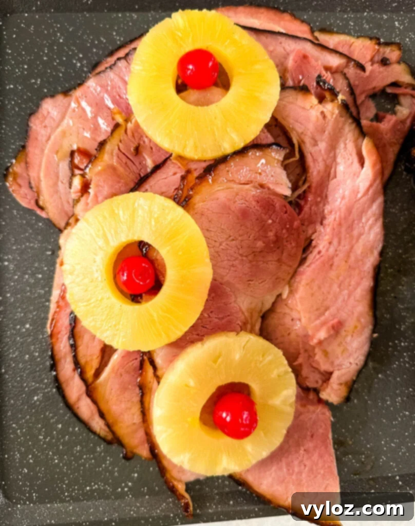 Traeger smoked ham sliced on a serving platter with pineapple rings and cherries, ready to be served