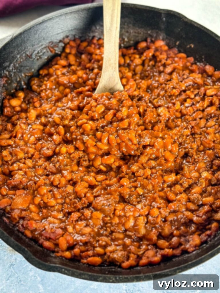smoked baked beans with ground beef and bacon in a cast iron skillet