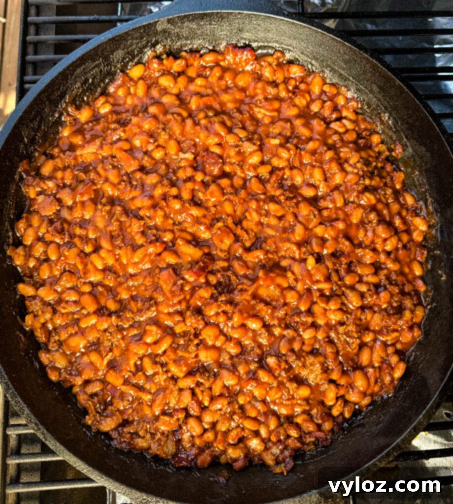 smoked baked beans with ground beef and bacon in a cast iron skillet
