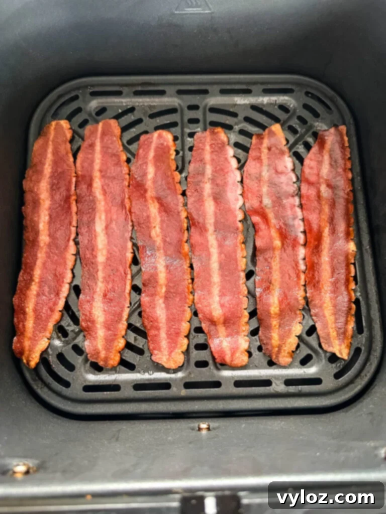 Perfectly cooked, crispy air fryer turkey bacon strips in an air fryer basket.