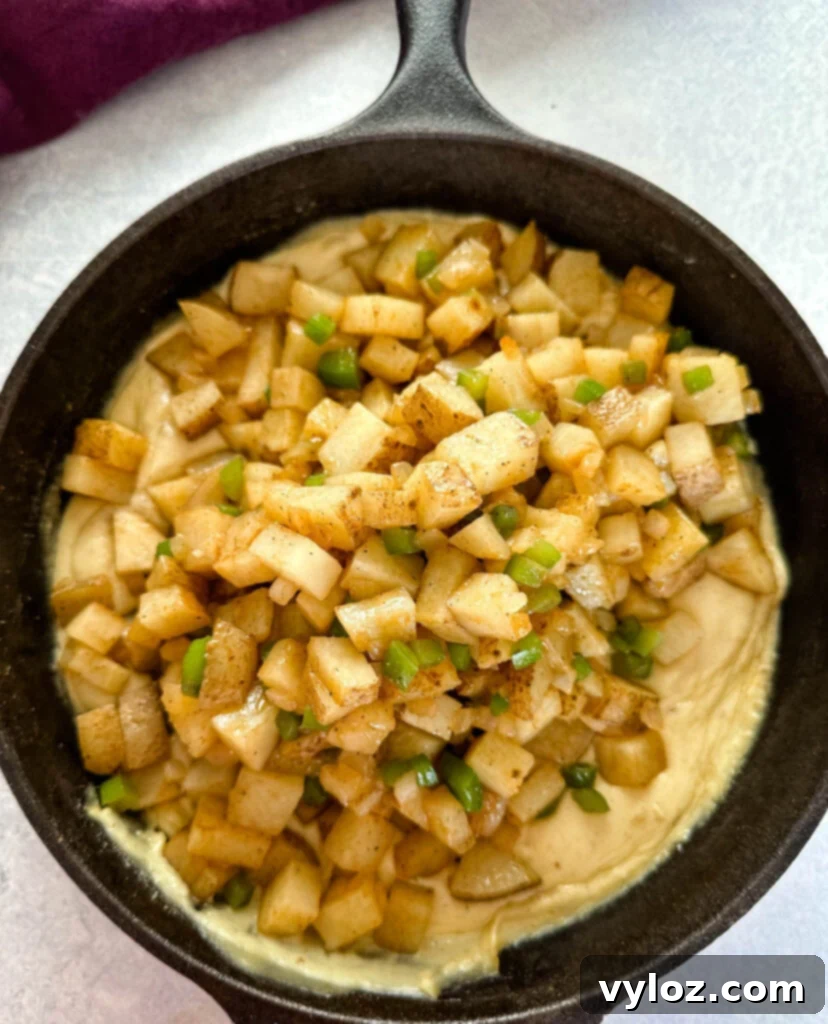 Savory Slow-Cooked Potatoes and Onions 11 Close-up of smothered potatoes with onions, peppers, and gravy in a cast iron skillet, ready to serve