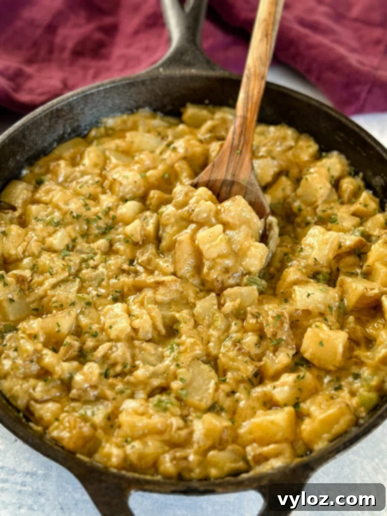 Savory Slow-Cooked Potatoes and Onions 12 A serving of smothered potatoes with onions, peppers, and gravy in a cast iron skillet