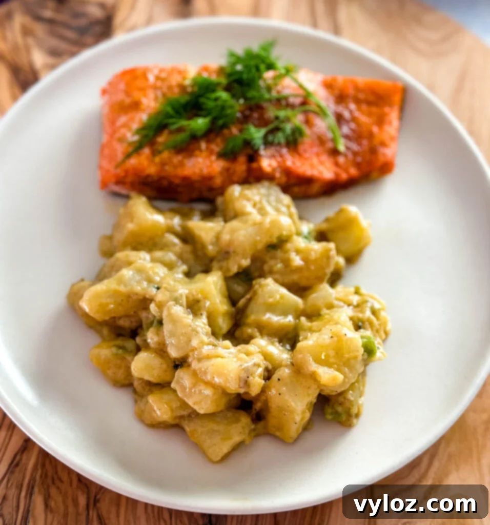 Savory Slow-Cooked Potatoes and Onions 13 Smothered potatoes served on a plate with baked salmon, showcasing a complete meal