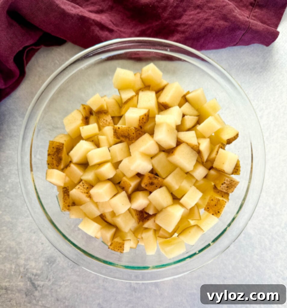 Savory Slow-Cooked Potatoes and Onions 4 Diced russet potatoes in a clear glass bowl, prepped for cooking