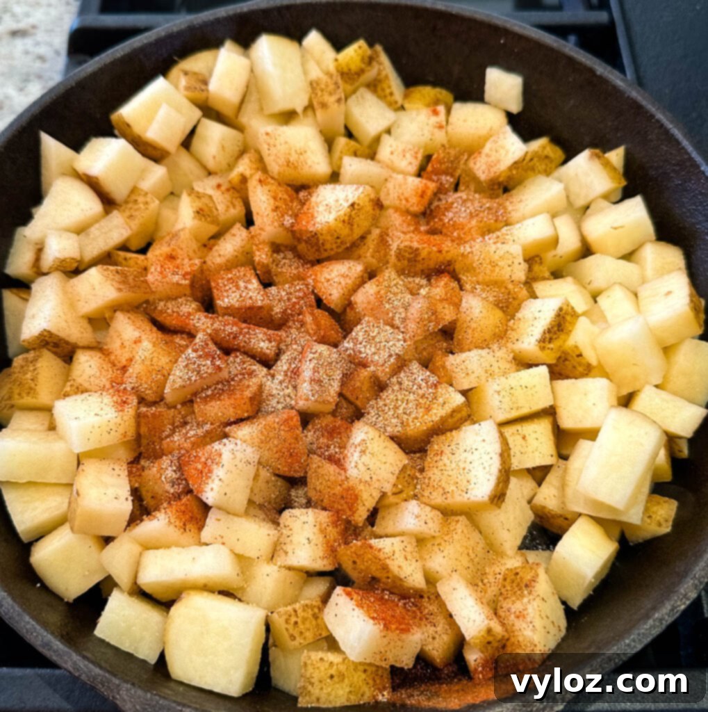 Savory Slow-Cooked Potatoes and Onions 5 Fried potatoes, onions, and peppers sizzling in a cast iron skillet, beginning to brown