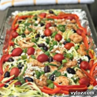 Mediterranean shrimp with zucchini noodles on a foil lined baking sheet
