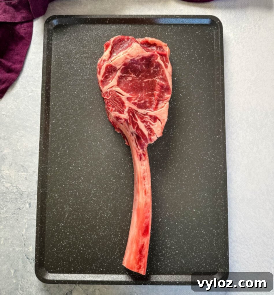 raw tomahawk steak with butter on a platter