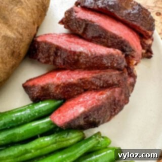 smoked filet mignon on a plate with green beans and a baked potato