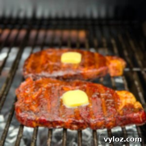 Traeger Wood Fired Ribeye 11 Smoked ribeyes with butter on a Traeger smoker grill, highlighting the rich color and juicy texture.