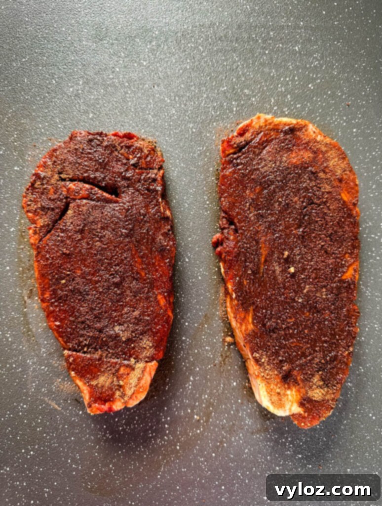 Traeger Wood Fired Ribeye 4 Raw, seasoned ribeye steaks resting on a plate, ready for the smoker.