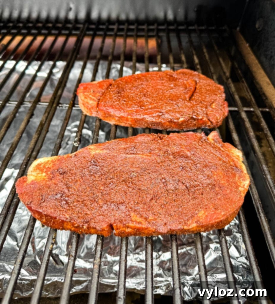 Traeger Wood Fired Ribeye 5 Raw seasoned ribeye steak on a Traeger smoker grill, ready for smoking.