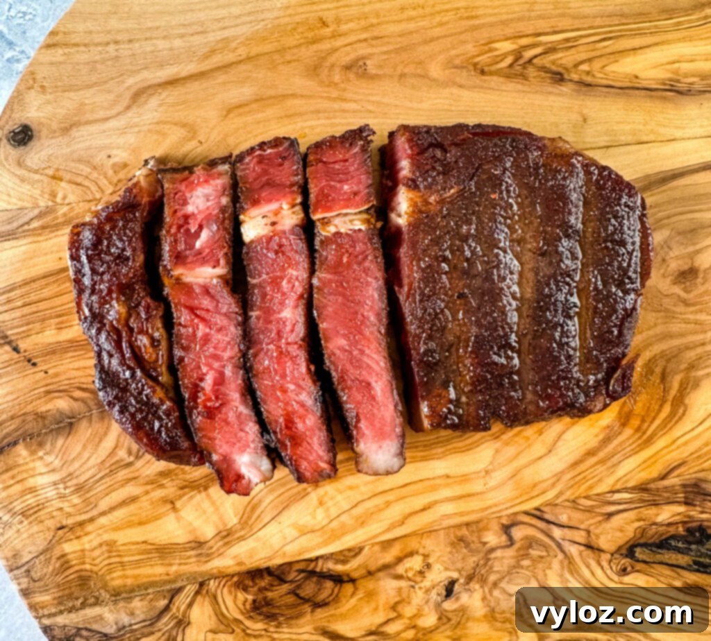 Traeger Wood Fired Ribeye 9 Perfectly sliced smoked ribeye steak on a cutting board, showcasing its juicy interior and smoke ring.