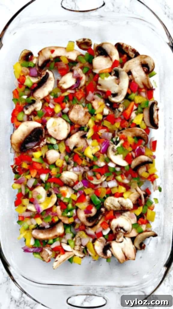 Assortment of fresh vegetable ingredients for Low-Carb Bacon, Egg, and Spinach Breakfast Casserole, including bell peppers, onions, and mushrooms, ready to be prepared in a glass pan