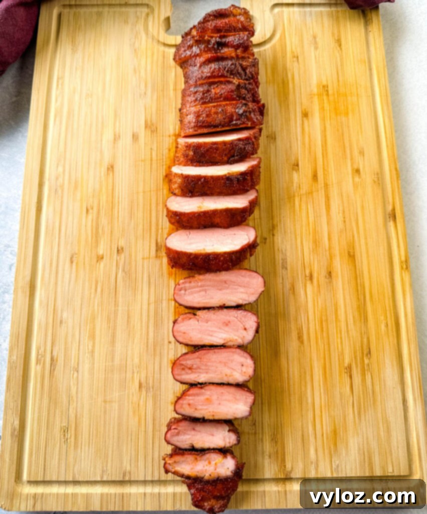 sliced smoked pork tenderloin on a wooden cutting board, perfectly cooked