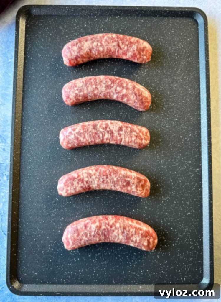 The Perfect Traeger Smoked Brats 3 uncooked brats on a sheet pan