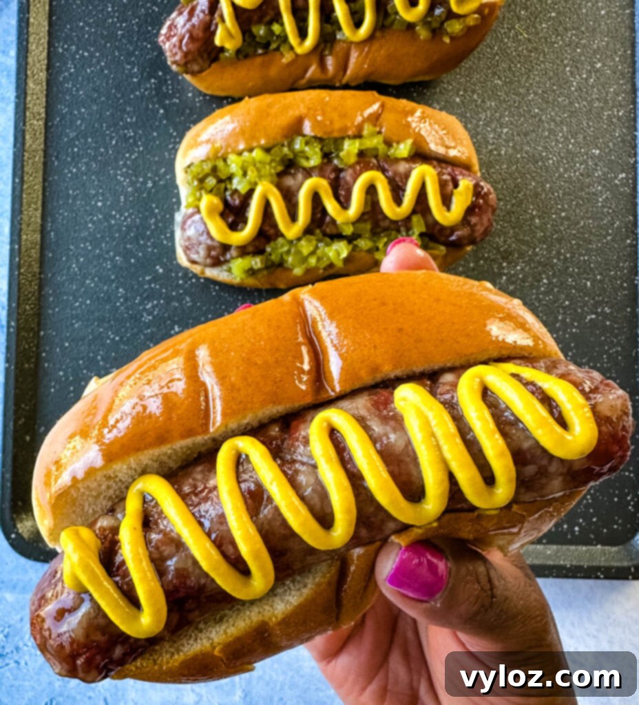 The Perfect Traeger Smoked Brats 10 person holding smoked brat on buns with mustard and relish