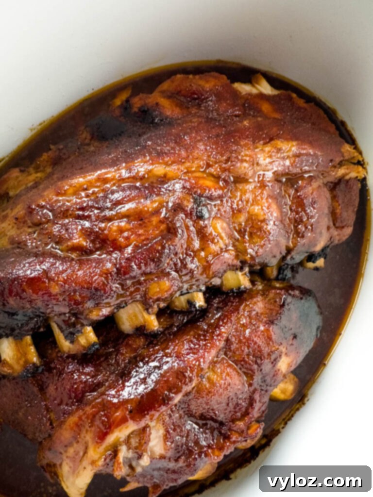 Slow Cooker BBQ Spare Ribs 2 BBQ ribs cooking in a Crockpot slow cooker, bathed in rich BBQ sauce, ready to be served