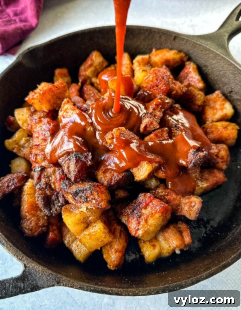smoked pork belly in a cast iron skillet drizzled with BBQ sauce