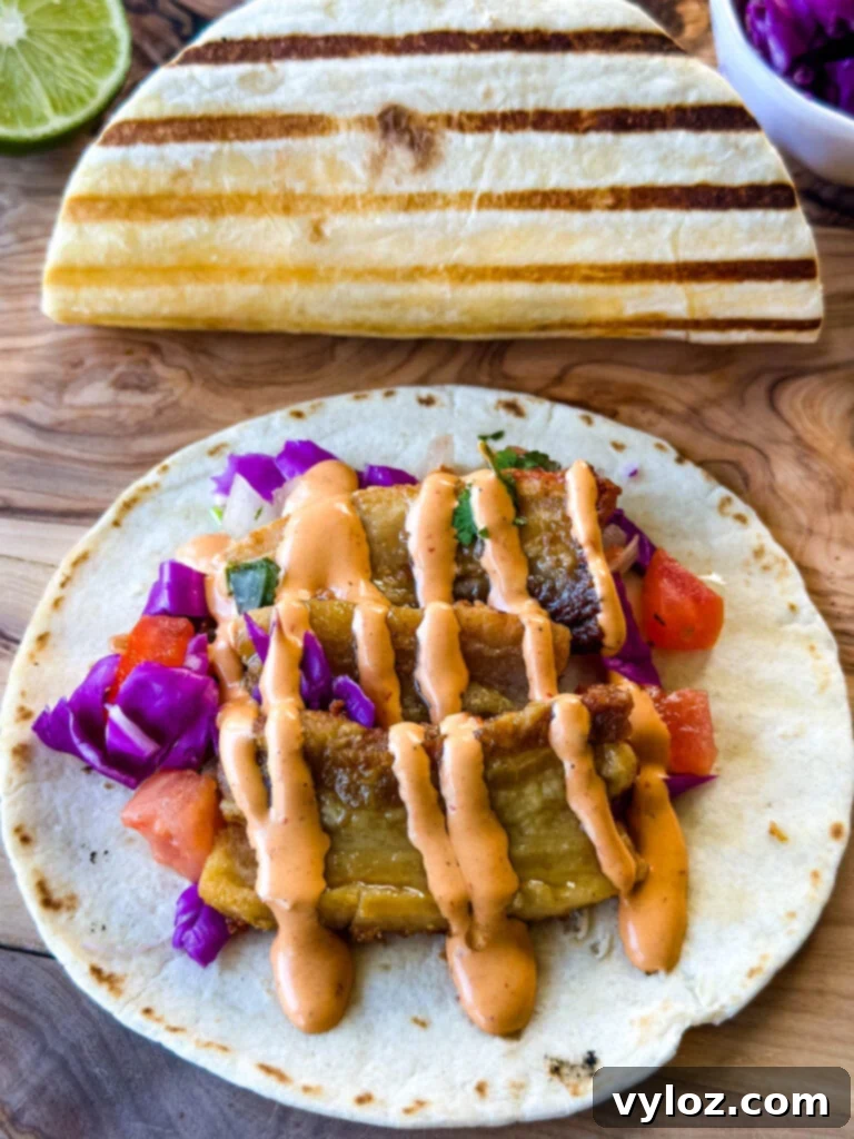 Crispy pork belly taco with seared flour tortilla, spicy Chipotle sauce, and fresh pico de gallo