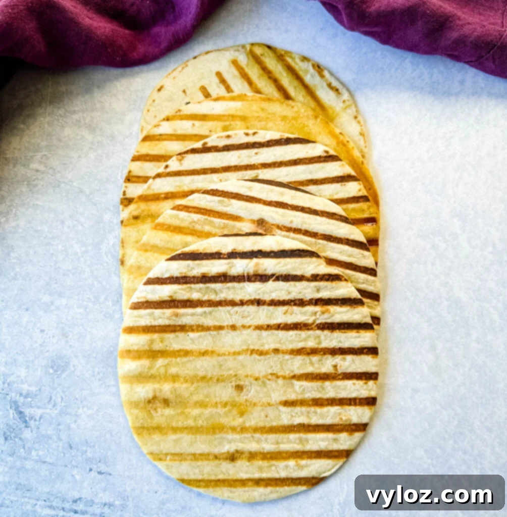 Perfectly seared flour tortillas resting on a flat surface, ready for filling