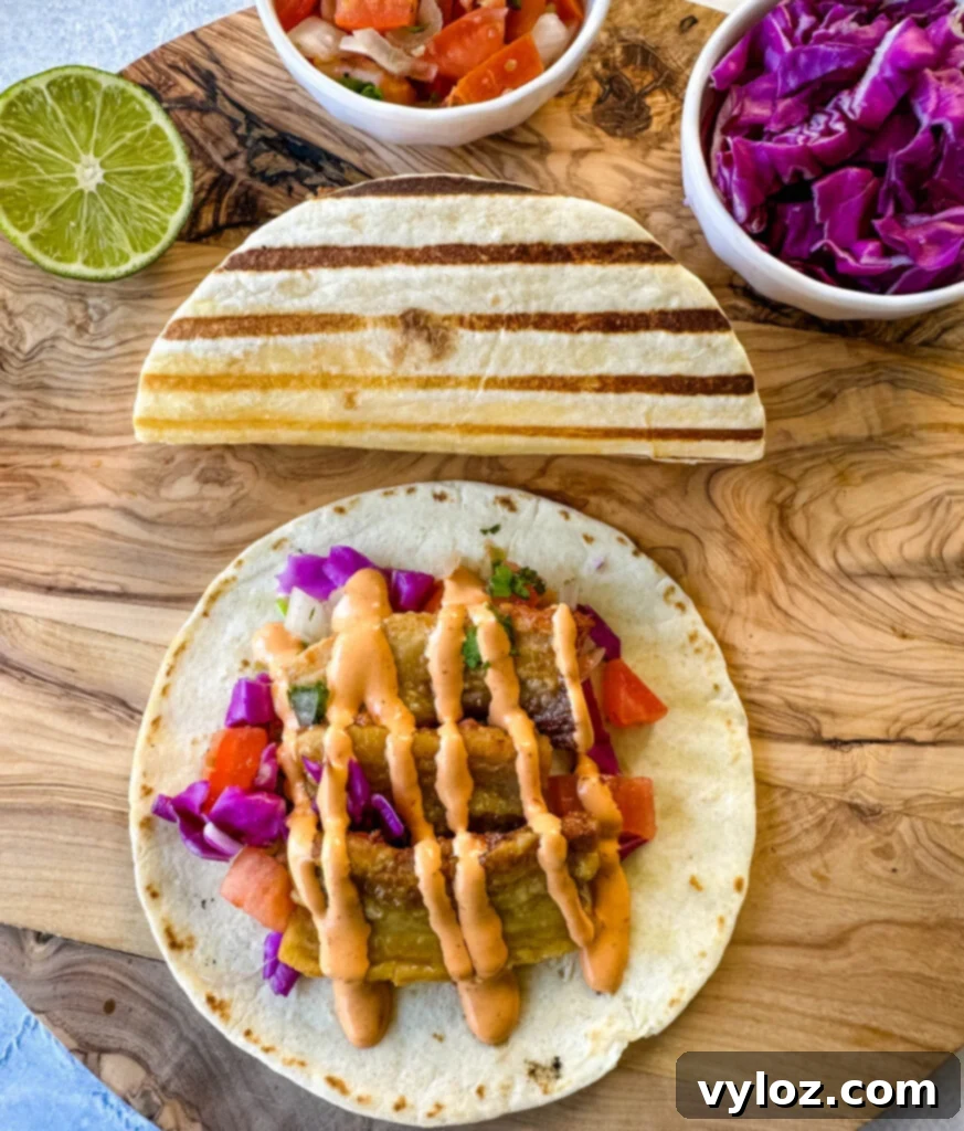 Three beautifully presented pork belly tacos on seared flour tortillas, garnished with spicy Chipotle sauce and pico de gallo