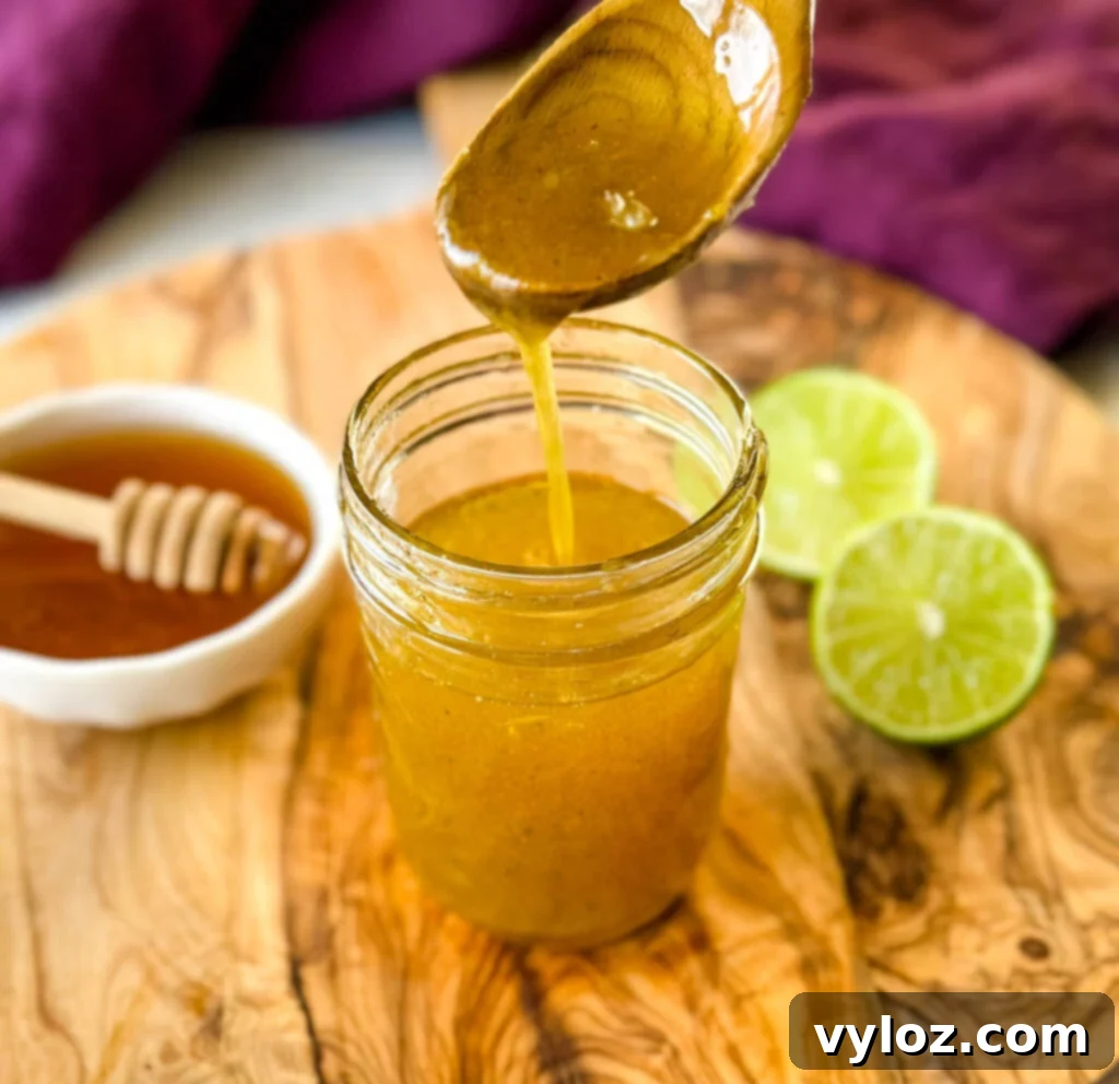 A spoonful of the creamy honey lime salad dressing carefully poised over a glass jar, ready for serving or storage.