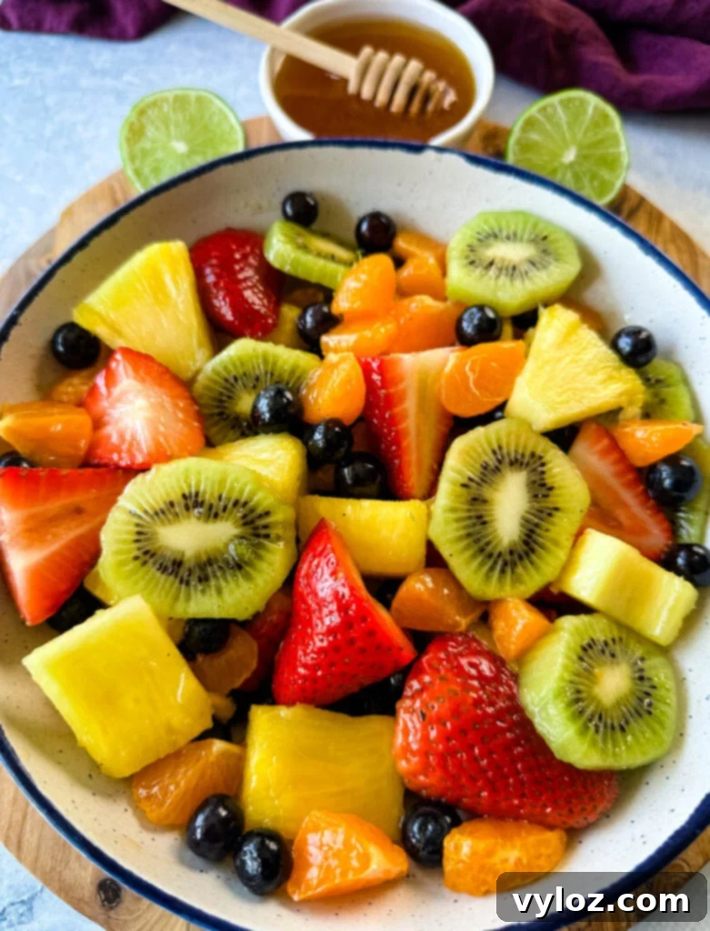 Refreshing Rainbow Fruit Medley 8 A refreshing fruit salad composed of succulent strawberries, juicy mandarin oranges, vibrant kiwi, plump blueberries, and sweet pineapple, served elegantly in a white bowl with a delicate honey lime dressing.