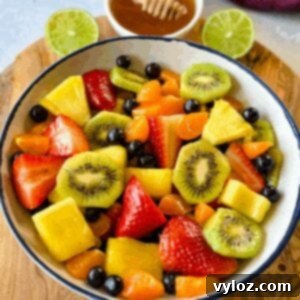 Refreshing Rainbow Fruit Medley 10 A vibrant mix of fresh strawberries, mandarin oranges, kiwi, blueberries, and pineapple fruit salad in a white bowl, ready to be served with honey lime dressing.