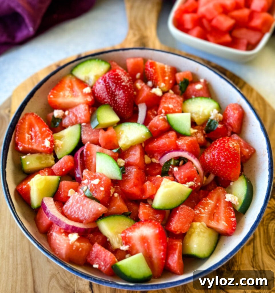 Vibrant Watermelon Feta Salad with Balsamic 2 watermelon salad with feta, basil, cucumbers, avocado, strawberries, onion, and balsamic lime dressing in a white bowl