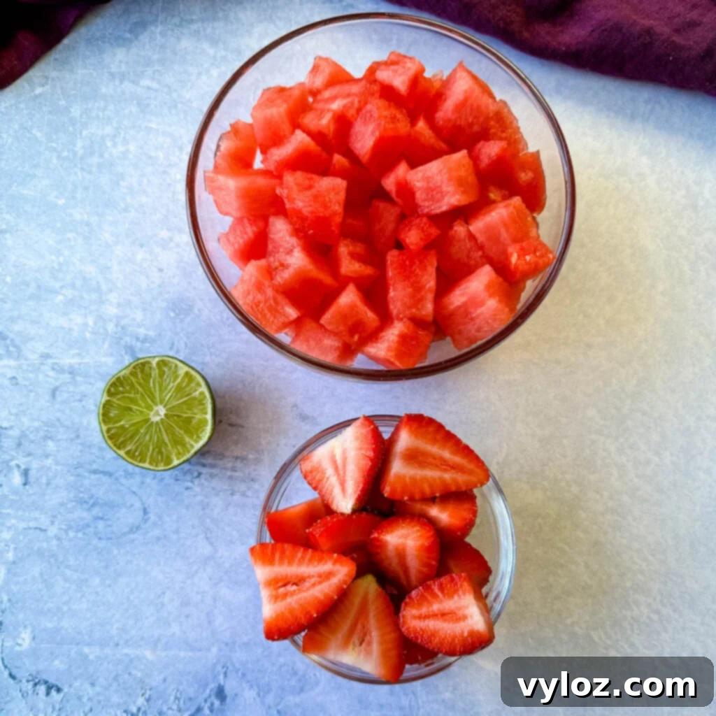 Vibrant Watermelon Feta Salad with Balsamic 3 diced watermelon, sliced strawberries, and a lime in separate glass bowls