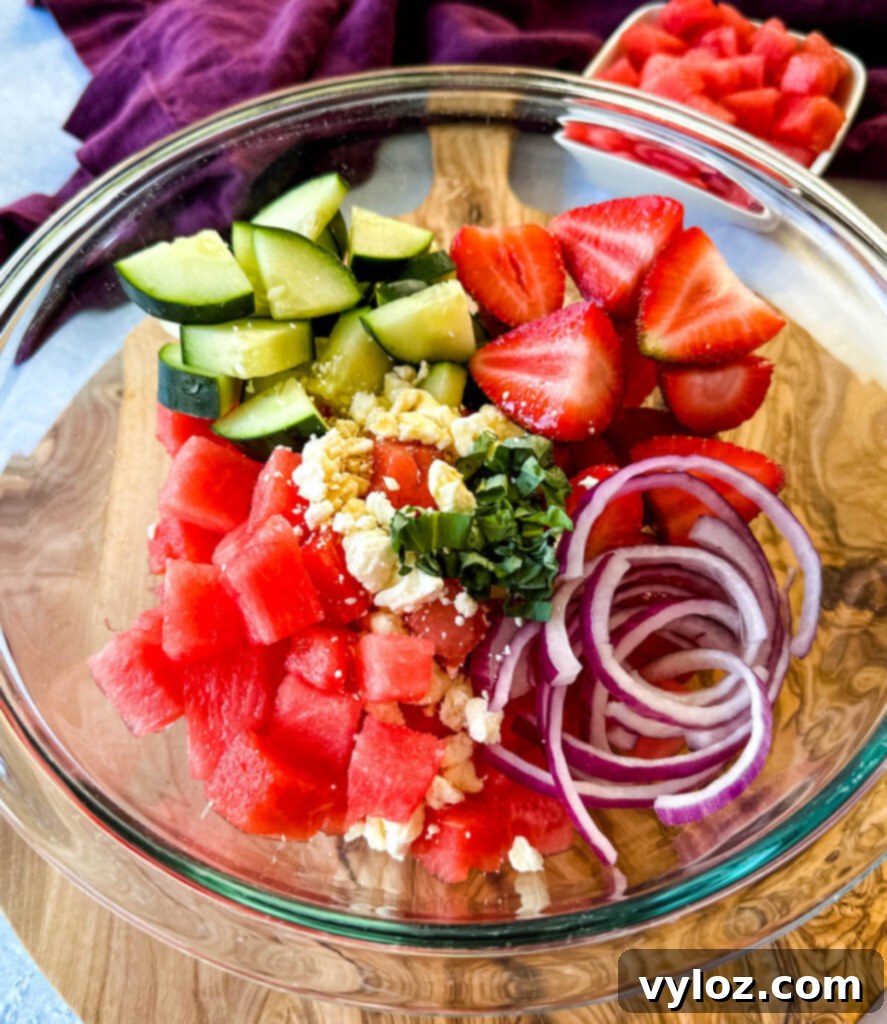 Vibrant Watermelon Feta Salad with Balsamic 6 watermelon salad with feta, cucumbers, avocado, basil, strawberries, onion, and balsamic lime dressing in a glass bowl