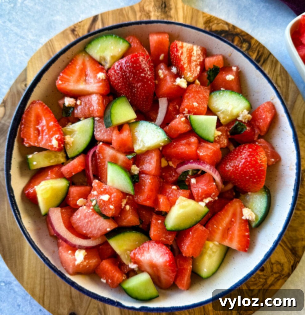 Vibrant Watermelon Feta Salad with Balsamic 8 watermelon salad with feta, basil, cucumbers, avocado, strawberries, onion, and balsamic lime dressing in a white bowl