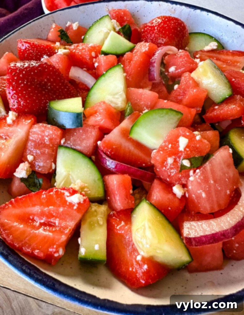 Vibrant Watermelon Feta Salad with Balsamic 9 watermelon salad with feta, basil, cucumbers, avocado, strawberries, onion, and balsamic lime dressing in a white bowl
